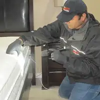 Bed bug inspection technician checking a mattress and bed frame for signs of infestation in Lakeland, FL