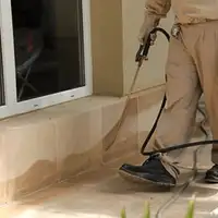 General pest control technician spraying exterior perimeter around a home in Lakeland, FL