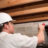 Termite inspection technician checking a basement wall and framing for termite activity in Lakeland, FL